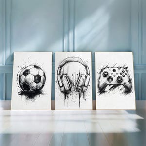 Könnte beinhalten: Drei gerahmte Kunstdrucke mit Schwarz-Weiß-Illustrationen. Die Drucke zeigen einen Fußball, Kopfhörer und einen Gamecontroller. Das Kunstwerk hat einen skizzenartigen Stil mit Tintenspritzereffekten, vor einem weißen Hintergrund.