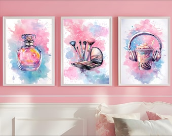 Op de afbeelding: Drie aquarellen in witte lijsten. De eerste aquarel heeft een roze en blauwe aquarel achtergrond met een heldere glazen fles parfum. De tweede aquarel heeft een roze en blauwe aquarel achtergrond met make-up kwasten en een make-up palet. De derde aquarel heeft een roze en blauwe aquarel achtergrond met een kopje boba thee en koptelefoon.