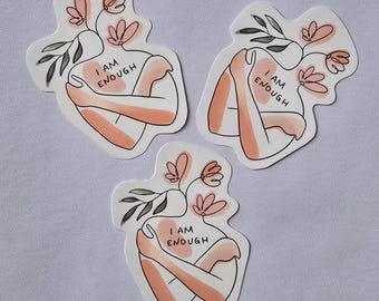 Könnte beinhalten: Drei Aufkleber mit einer Strichzeichnung einer Person, die sich selbst umarmt. Der Körper der Person ist pfirsichfarben, mit einem Blumendesign, das aus dem Kopf wächst. Der Text "I AM ENOUGH" ist auf die Brust gedruckt.