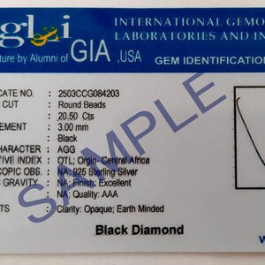 May include: A gem identification report from IGLI USA, featuring details of a black diamond. The card includes the certificate number, shape, weight (20.50 Cts), and measurement (3.00 mm). The text "Black Diamond" is visible.