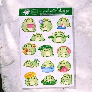 May include: A sheet of stickers featuring various green frog illustrations. Each frog is depicted in different poses and activities, such as reading, holding flowers, or wearing headphones. The sheet includes the text "vivid mist design".