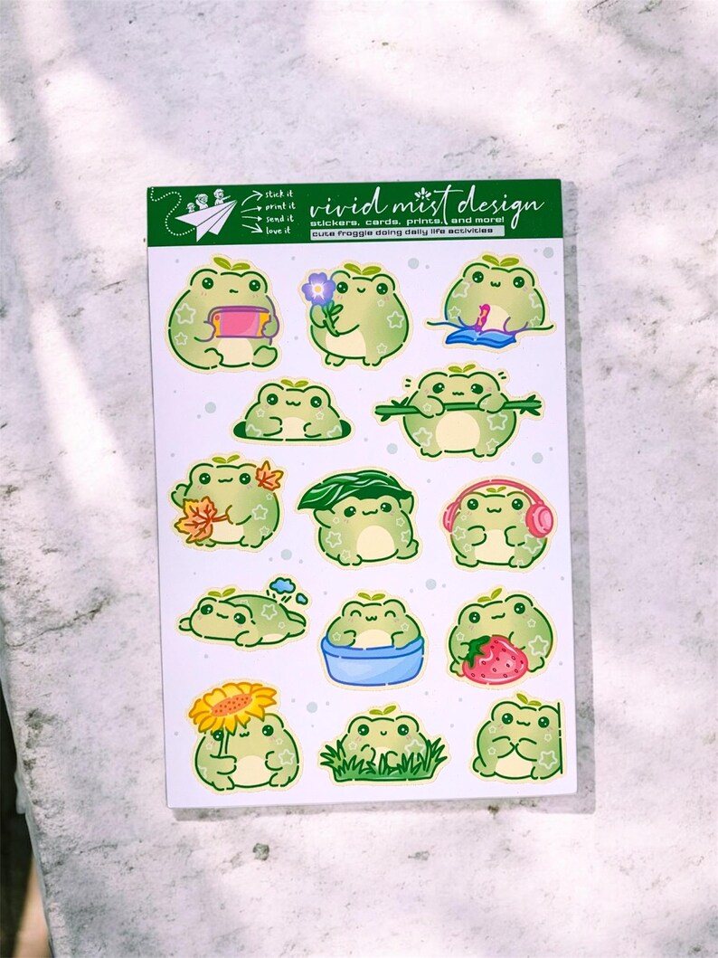 May include: A sheet of stickers featuring various green frog illustrations. Each frog is depicted in different poses and activities, such as reading, holding flowers, or wearing headphones. The sheet includes the text "vivid mist design".