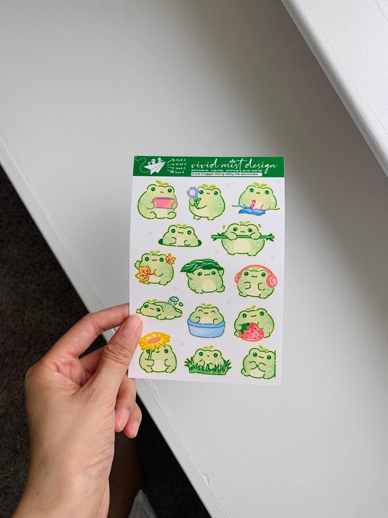 Other frogs are shown enjoying simple pleasures such as listening to music with pink headphones, holding a strawberry nearly as big as itself, resting with sleepy eyes, or clutching a long green branch with a content grin. The frogs share a consistent color palette of soft green tones, creamy bellies, rosy cheeks, and tiny star accents that add charm without overwhelming the design.