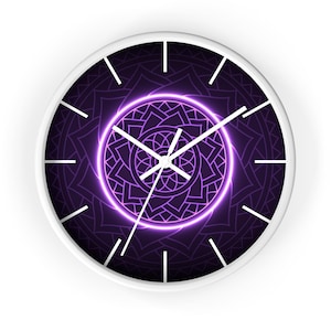 May include: A round wall clock with a white frame. The clock face features a dark purple mandala design with a glowing purple circle in the center. White hands and hour markers complete the design.