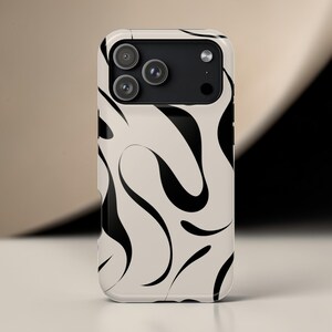 Pode incluir: Uma capa de telefone com fundo creme e um padrão ondulado abstrato preto. A capa tem um módulo de câmera com três lentes. O design é moderno e minimalista.