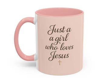 Op de afbeelding: Een witte keramische mok met een roze binnenkant en handvat. De mok heeft de tekst "Just a girl who loves Jesus" in een scriptlettertype, met een klein kruisje eronder.