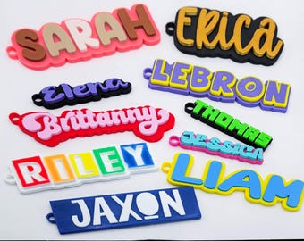 May include: A collection of colorful, 3D printed name tags with various names including Sarah, Erica, LeBron, Brittany, Thomas, Jessica, Liam, Riley, Jaxon, and Elena.