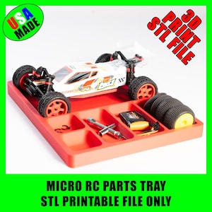 Puede incluir: Una bandeja roja para piezas de micro RC con un coche RC blanco y naranja, neumáticos de repuesto y herramientas. La bandeja tiene múltiples compartimentos para organizar las piezas. Incluye el texto "USA MADE" y "3D PRINT STL FILE".