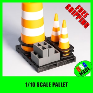May include: A 1/10 scale pallet with three orange and white traffic cones and a stack of gray concrete blocks. The pallet is made in the USA and is available for free shipping.