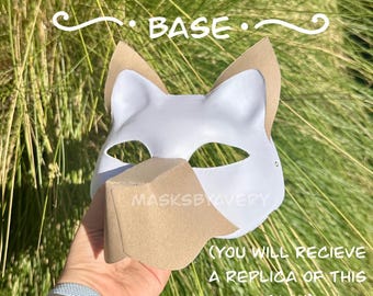 May include: A white canine therian mask base with tan ears and nose. The mask has eye cutouts and is held in front of a green background. Text on the mask reads "CANINE THERIAN MASK BASE" and "MASKSBYAVERY".