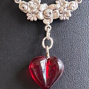 Colar com pingente de coração em vidro vermelho vintage, adornado com guirlanda floral prateada e corrente retangular em prata de lei.