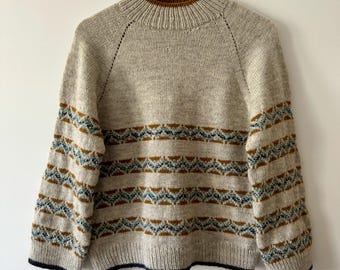 May include: A beige knitted sweater with brown, blue, and white stripes. The sweater has a mock neck and long sleeves.