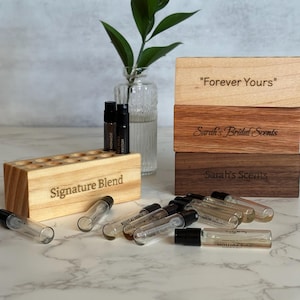 May include: A white ceramic mug with a black handle and the text "But First, Coffee" in a bold, black font. The mug is set against a blurred background, suggesting a cozy setting.