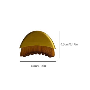 May include: A makeup brush with a gold-colored handle and a brown, densely packed brush head. The brush is 3.15 inches wide and 2.17 inches tall. The brush is designed for applying makeup.