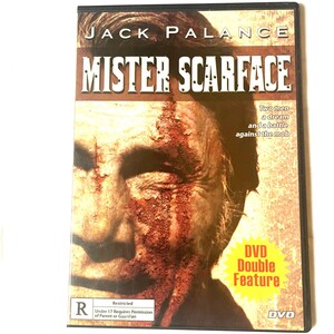 May include: DVD cover for the movie "Mister Scarface" starring Jack Palance. The cover features a close-up of Palance's face with red and brown makeup, giving the appearance of a scar. The text "DVD Double Feature" is in a yellow box on the right side of the cover.