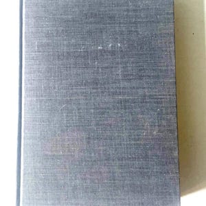 May include: A dark gray hardcover book with a textured fabric cover.