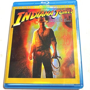 May include: A blue Blu-ray case featuring the movie "Indiana Jones and the Kingdom of the Crystal Skull." The cover art shows a man in a fedora holding a whip, with the title in large, yellow letters.