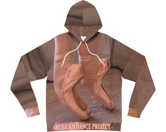 Puede incluir: Una sudadera con capucha marrón con una impresión de los pies de una bailarina en puntas. El texto "AMERICAN DANCE PROJECT" está impreso en la parte inferior de la sudadera.