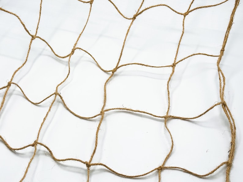 May include: A brown, woven, square-shaped net made of natural fibers. The net has a grid pattern with square openings.