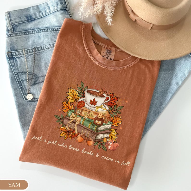 Yam Comfort Colors shirt featuring stacked books, hot cocoa, autumn leaves and a cute squirrel with the phrase “Just a Girl Who Loves Books & Cocoa in Fall,” a cozy fall reading shirt for book lovers.