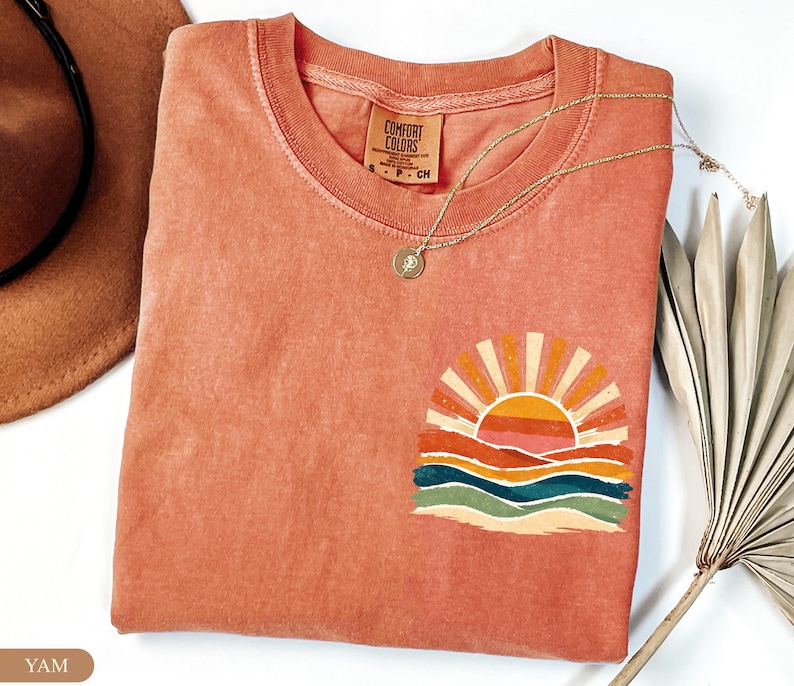 Folded Comfort Colors® t-shirt in color Yam featuring a vintage retro ocean sun graphic with warm sunset-inspired tones. Cute women shirt with beach vacation aesthetic, summer vibes style, and sunshine design perfect for coastal outfits and trendy summer looks.