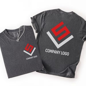 May include: Two charcoal gray t-shirts featuring a red and white geometric logo and the text COMPANY LOGO. One shirt displays the logo on the left chest, while the other shows a larger version of the same logo and text on the back.