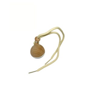 Op de afbeelding: Een houten diffuserbal met een beige koord eraan. De bal heeft een lichte houtnerf en een witte streep rond het midden.
