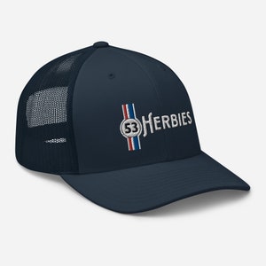 May include: A navy blue trucker hat with a white mesh back. The front of the hat features an embroidered logo with the text "53 HERBIES" in white and a red, white, and blue stripe design.