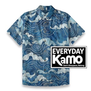 May include: Short-sleeved button-down shirt with a blue and white wave pattern. The shirt features a chest pocket and a collar. The text "EVERYDAY Kamo" is displayed in a black and white box.