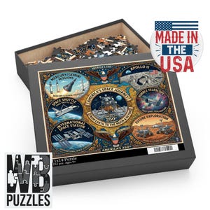 May include: A 252-piece puzzle in a black box, featuring an illustration of America's space journey. The puzzle includes images of the Mercury/Gemini missions, Space Shuttle, International Space Station, and Apollo 11. The box reads "Made in the USA."