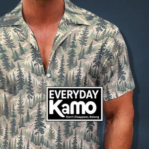 May include: Short-sleeved button-down shirt with a forest-themed camouflage pattern. The shirt features a notched collar and a white button. The text "EVERYDAY Kamo" is displayed in a black and white rectangular box, with the tagline "Don't Disappear, Belong."