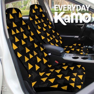 Pode incluir: Um par de capas para assentos de carro com fundo preto e um padrão repetitivo de triângulos amarelos e cinza escuro. O texto "EVERYDAY Kamo" é visível no canto superior direito da imagem, sobreposto à vista do interior do carro.