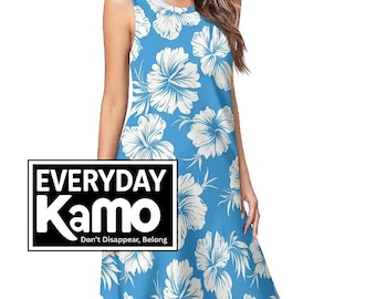Peut inclure: Robe bleue sans manches ornée d'un motif floral blanc. La robe arrive au genou et présente une encolure ronde. Le texte "EVERYDAY Kamo" est affiché dans un encadré noir avec le slogan "Don't Disappear, Belong."