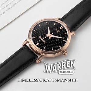 May include: A rose gold wristwatch with a black textured face and black leather band. The watch face features white hands and hour markers. The brand name "WARREN WATCH CO." and the phrase "TIMELESS CRAFTSMANSHIP" are displayed.