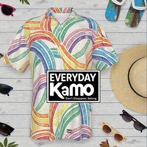 May include: A short-sleeved shirt with a colorful rainbow design. The shirt has a white background with a pattern of curved lines in various colors. The shirt has the text "EVERYDAY Kamo" in a black box. Sunglasses and a straw hat are also visible.