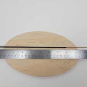 May include: A black incense stick measuring approximately 9 inches (23 cm) in length, placed on a wooden surface with a ruler for scale.