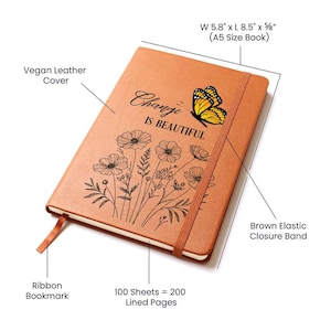 Puede incluir: Un diario de cuero vegano marr&oacute;n con el texto "Change is Beautiful" y una ilustraci&oacute;n de mariposa. El diario tiene una cinta de marcador y una banda el&aacute;stica de cierre. Mide 14,7 cm x 21,6 cm x 1,6 cm y contiene 200 p&aacute;ginas rayadas.