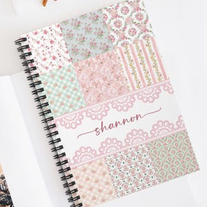 Könnte beinhalten: Ein rosa-grünes Spiralnotizbuch mit Patchwork-Design, das florale Muster und Spitze zeigt. Das Notizbuch trägt den Namen "shannon" auf der Vorderseite.
