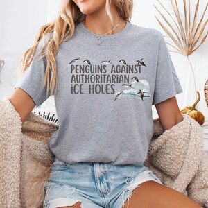 Make a bold (and chilly) statement with this hilarious penguin protest tee! Featuring the phrase “Penguins Against Authoritarian Ice Holes” in bold font, this shirt shows penguins standing proud above the text and perched on a floating chunk of ice. It’s perfect for protests, marches, or any day you feel like calling out cold-hearted nonsense. Available in 7 colors, it's a comfy, conversation-starting way to stand up (or waddle) for what’s right.