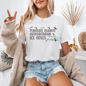 Make a bold (and chilly) statement with this hilarious penguin protest tee! Featuring the phrase “Penguins Against Authoritarian Ice Holes” in bold font, this shirt shows penguins standing proud above the text and perched on a floating chunk of ice. It’s perfect for protests, marches, or any day you feel like calling out cold-hearted nonsense. Available in 7 colors, it's a comfy, conversation-starting way to stand up (or waddle) for what’s right.