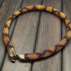 Statement gold beaded snake choker necklace, ouroboros, bronze-colored clasp in the shape of a snake's head biting its tail.