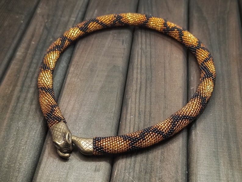 Statement gold beaded snake choker necklace, ouroboros, bronze-colored clasp in the shape of a snake's head biting its tail.