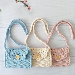 Peut inclure: Trois petits sacs à main au crochet de couleurs pastel : bleu clair, crème et rose. Chaque sac a un rabat festonné, une fermeture à bouton en bois et une bandoulière assortie. Les sacs sont faits à la main et adaptés aux enfants.
