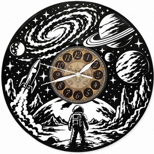 May include: A circular wall clock crafted from a black vinyl record featuring a white space-themed illustration of an astronaut standing on a lunar surface, a rocket launching, planets, and a galaxy. The center dial has a vintage-style clock face.