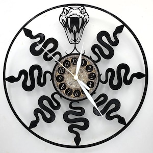 May include: Black and white wall clock featuring a snake design. The clock has a circular frame with black snakes encircling a central clock face. The clock face has Roman numerals and white clock hands.