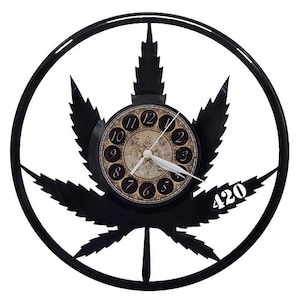 May include: Black wall clock featuring a cannabis leaf design. The clock face has a vintage style with black numerals and hands. The number "420" is displayed in white. The clock is round and has a black frame.
