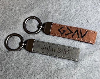 May include: Two leather keychains with metal rings. One keychain is brown with the word "G>A>V" in black lettering. The other keychain is gray with the text "John 3:16" in black lettering.
