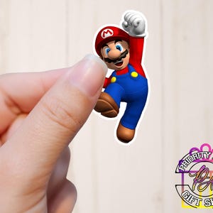 May include: A red and blue cartoon character with a mustache and a red cap with an 'M' on it. The character is jumping with his arms raised.