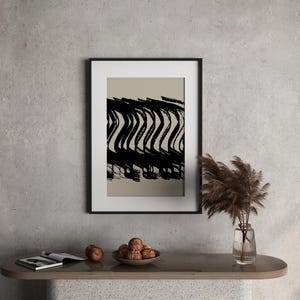 May include: Black and white abstract art print in a black frame. The artwork features bold, wavy brushstrokes against a neutral background. The framed art is displayed on a modern console table with decorative items.