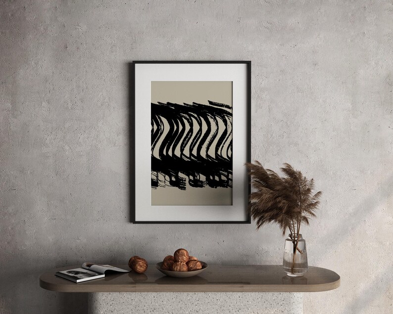 May include: Black and white abstract art print in a black frame. The artwork features bold, wavy brushstrokes against a neutral background. The framed art is displayed on a modern console table with decorative items.